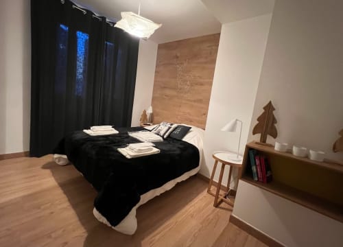 Chambre moderne à Couleurs Montagne, Valloire avec lit noir, finitions bois et vue sur les montagnes