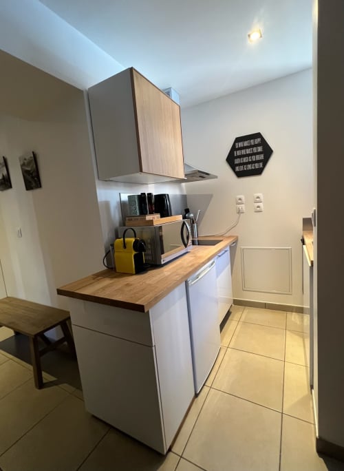 Kitchenette moderne de l'appartement Jaune Génépi à Couleurs Montagne, Valloire, avec meubles blancs et plan de travail en bois