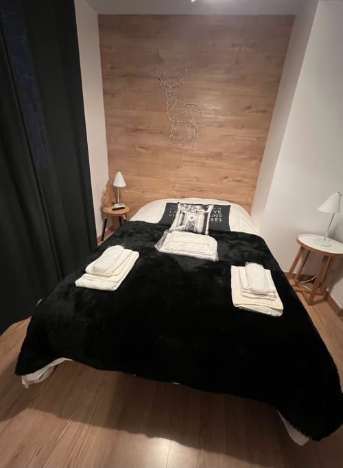 Chambre moderne à Couleurs Montagne, Valloire avec lit noir, art géométrique de cerf, mur en bois et décor alpin
