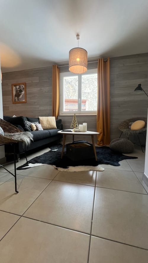 Salon moderne de l'appartement Jaune Génépi à Couleurs Montagne, Valloire avec canapé noir, luminaire suspendu et montagne