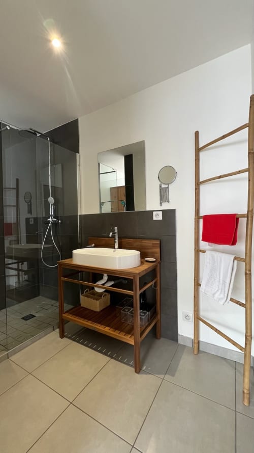 Salle de bain moderne de l'appartement Rouge Canneberge à Couleurs Montagne, Valloire, avec meuble vasque en bois, douche et sèche-serviettes chauffant