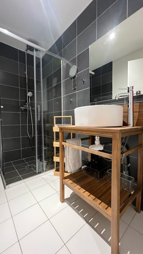 Salle de bain moderne à Couleurs Montagne avec douche carrelée noire, meuble vasque en bois et lavabo blanc à Valloire