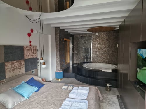 Suite di lusso a Rio Botteniga con letto, bagno privato con piastrelle nere, pareti a mosaico e vasca idromassaggio