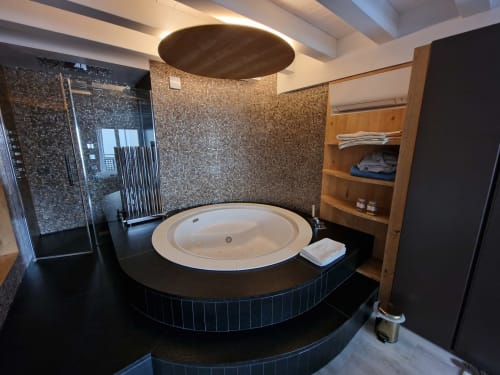 Lussuoso bagno spa a Rio Botteniga con vasca circolare incassata, rivestimenti in mosaico, doccia a pioggia e mobiletto in legno