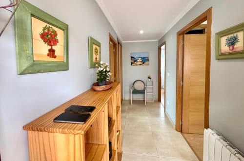 Moderno pasillo en la casita Holibai, Laranxeira, con puertas de madera, arte botánico enmarcado, consola decorada y vistas al mar