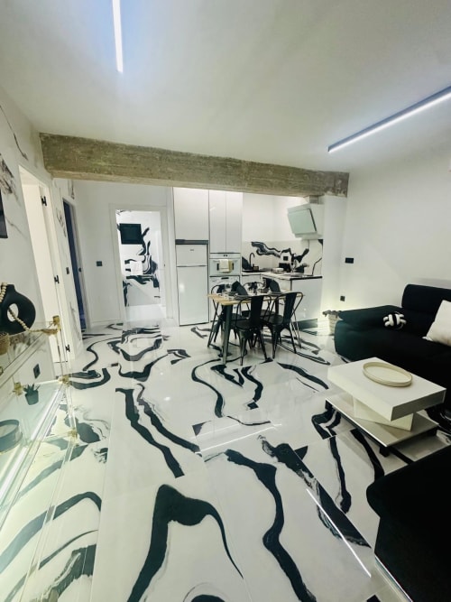 Apartamento moderno en Mérida con paredes blancas, piso con patrón negro, comedor, cocina y sofá verde oscuro