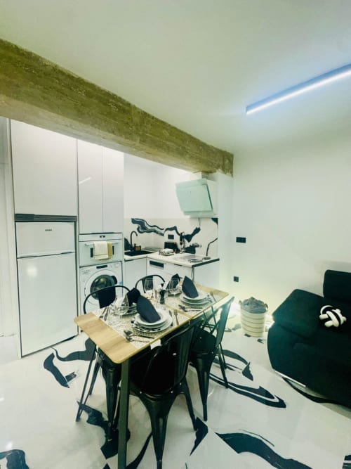 Moderna zona de cocina-comedor en apartamento de Mérida con electrodomésticos blancos, mesa de madera y viga de techo verde