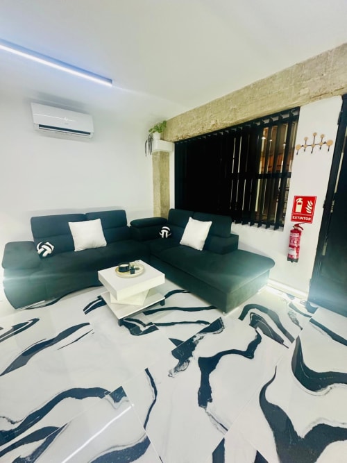 Sala moderna de departamento en Mérida con sofá seccional color turquesa, acentos blancos y patrón geométrico en el piso