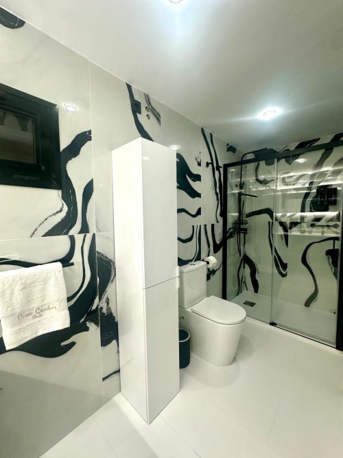 Baño moderno en apartamento de Mérida con arte abstracto en blanco y negro, tocador blanco, cabina de ducha de vidrio y
