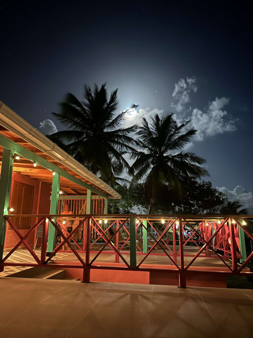 Exterior de la boutique lodge Seaflower de noche con barandales rojos, columnas verdes, palmeras y cielo iluminado por la luna en San Andrés