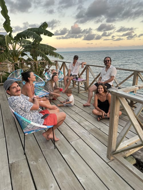 Grupo de huéspedes relajándose en la terraza de madera de Seaflower boutique lodge con vistas al mar Caribe al atardecer, San Andrés.