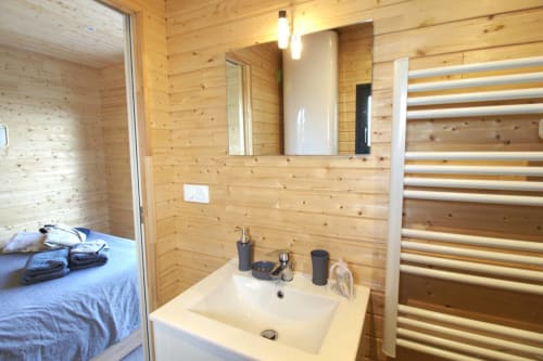 Modern bathroom in wood cabin at Ilot Cosy and Spa with white sink, mirror, and heated towel rack