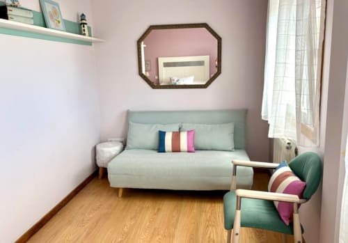Sofá verde menta con cojines coloridos en la sala de estar del pazo de Laranxeira, Nigrán, con suelos de madera y espejo con vista al mar