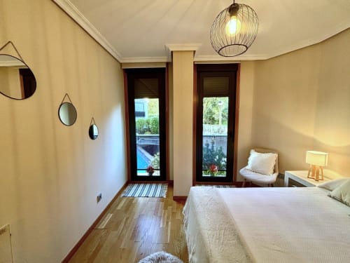 Dormitorio luminoso en Holibai Baiona con vista a la piscina, pisos de madera, lámpara colgante moderna y acceso a balcones