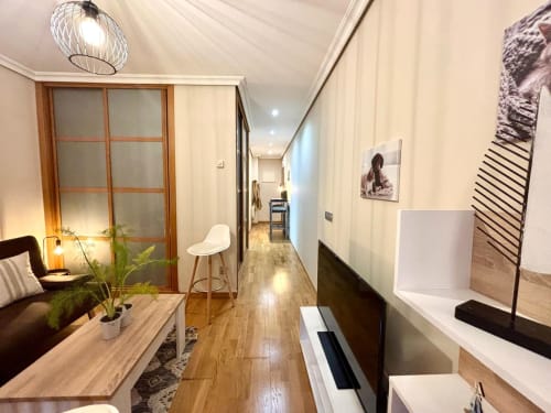 Sala moderna de apartamento en Baiona con suelo de madera, mobiliario confortable, televisor y pasillo hacia la zona de cocina