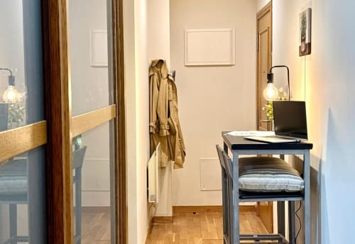 Recepción moderna del apartamento en Holibai Baiona con escritorio, silla, perchero e iluminación cálida