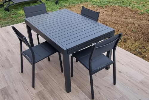 Modern black outdoor dining set with extendable table on wooden deck at Ilot Cosy and Spa