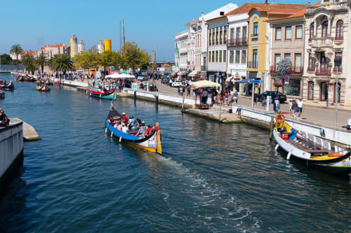 Barcos coloridos e arquitetura tradicional ao longo do canal pitoresco da frente de água de Aveiro num dia ensolarado