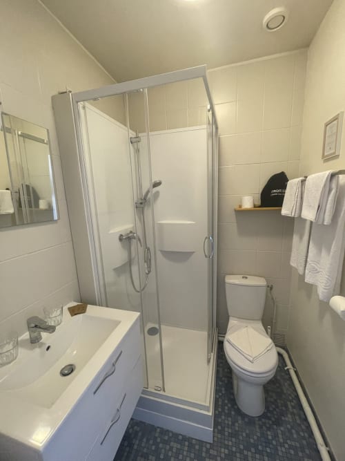 Clean bathroom at Hotel Le Trouville with glass shower enclosure, white vanity, and tiled flooring