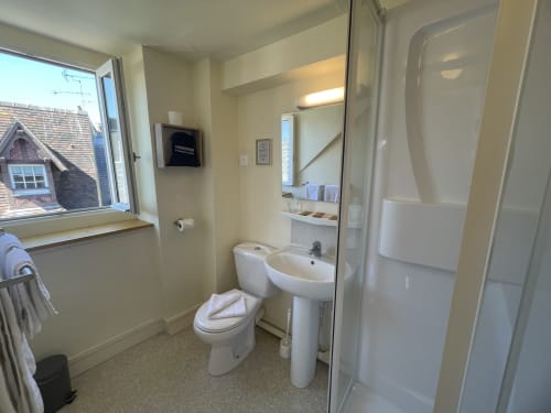 Clean bathroom with toilet, pedestal sink, shower at Hotel Le Trouville in Trouville sur Mer