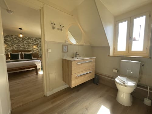 Ensuite bathroom with wooden vanity, round mirror, and toilet in Hotel Le Trouville room, Trouville sur Mer