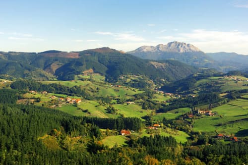 Pintoresco valle vasco con colinas verdes, bosques y casas de tejado rojo esparcidas cerca de Villa Ongizatea en Urrugne, Francia