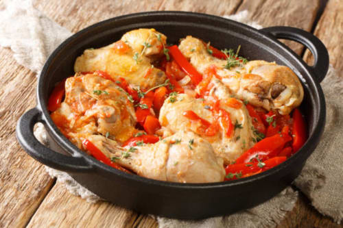 Pollo braseado con pimientos rojos en olla de hierro fundido negro en Villa Ongizatea, País Vasco francés