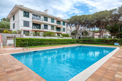 Shared swimming pool at Finques Garcia Enrich apartment hotel in Palafrugell with terracotta patio and modern white building
