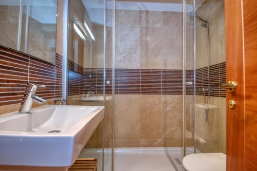 Modern bathroom with walk-in shower, white sink, and warm wood accents at Finques Garcia Enrich apartment in Palafrugell