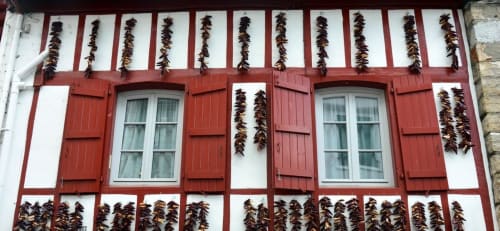 Arquitectura tradicional vasca en Villa Ongizatea con persianas rojas y pimientos secándose, Urrugne