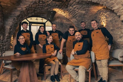 Team van Provence Km28 B&B in Gordes, Frankrijk, dragend bijpassende schorten in stenen kelderruimte