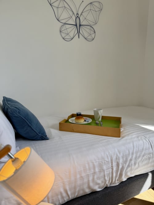 Single bed in the Dombes room with white linens, blue cushion, and breakfast tray placed on the mattress.