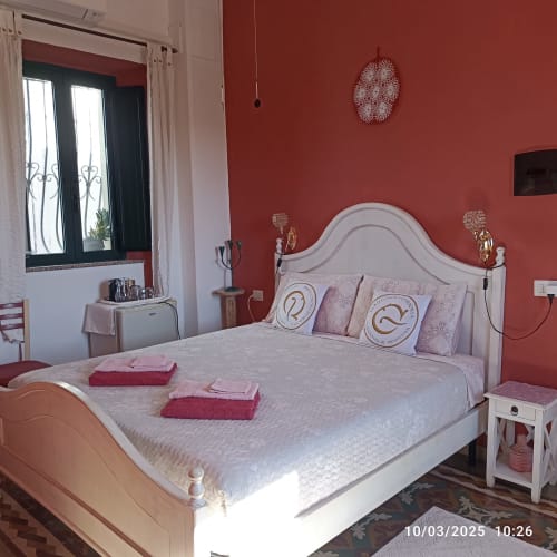 Camera elegante presso B&B Eleonora D'Arborea a Posada con pareti rosse, letto bianco e cuscini decorativi