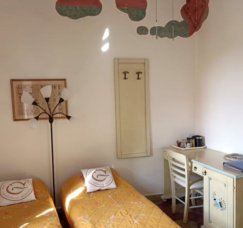 Camera accogliente del B&B Eleonora D'Arborea a Posada con copriletto giallo, lampada decorativa e piante sospese