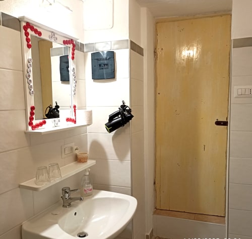 Bagno del B&B Eleonora D'Arborea a Posada con lavabo bianco, specchio decorativo e porta della doccia