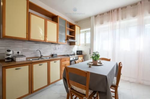 Moderna zona pranzo della cucina a House Live Express a Quartu Sant'elena con mobili in legno e tavola apparecchiata