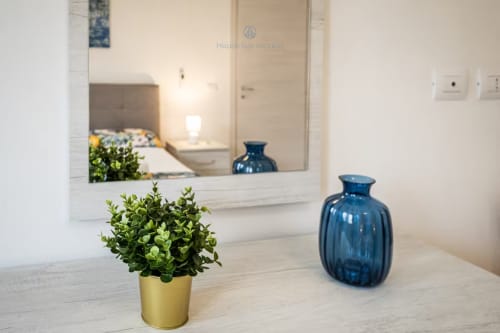Suite moderna presso House Live Express Quartu Sant'Elena con arredamento minimalista, pianta in vaso e vasi blu in vetro
