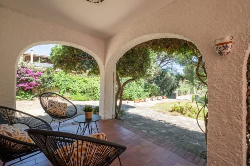 Patio coperto con arcate, lettini neri e vista sul giardino presso House Live Express, Quartu Sant'Elena
