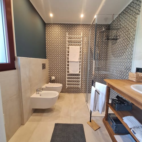 Modern bathroom at Locanda del Sasso Rooms with walk-in shower, patterned tilework, and wooden vanity in Crodo