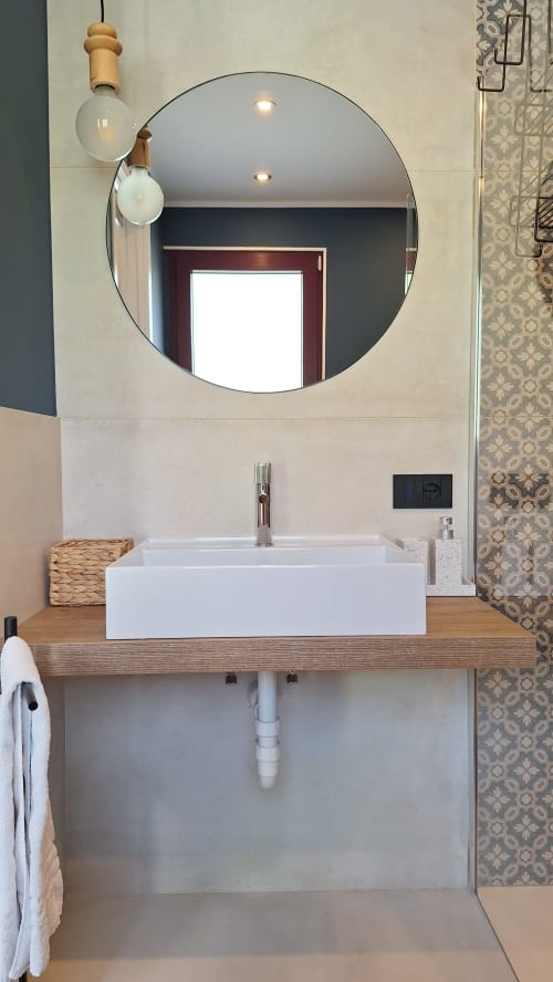 Modern bathroom at Locanda del Sasso Rooms in Crodo with circular mirror, white vessel sink, and wooden vanity