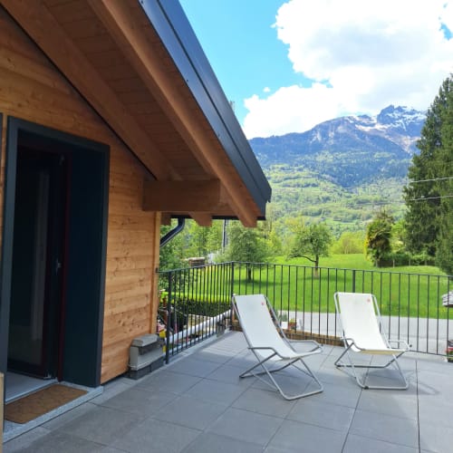 Wooden chalet terrace with loungers overlooking alpine mountains at Locanda del Sasso, Crodo