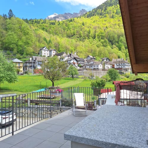 Terrace view at Locanda del Sasso Rooms in Crodo with lounger, mountains, and village nestled in green valley