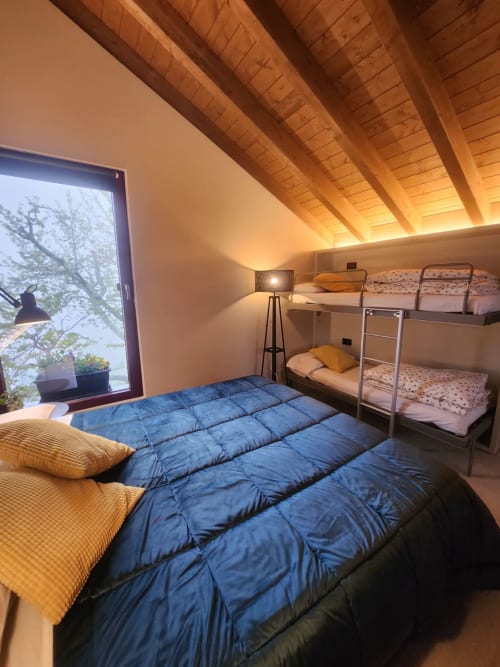 Cozy attic bedroom at Locanda del Sasso with exposed wooden beams, bunk beds, and mountain views in Crodo