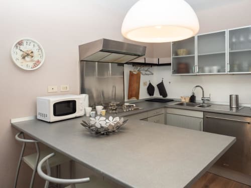 Cucina moderna nell'appartamento SleepWithMe Luxury B&B Pisa con isola, elettrodomestici in acciaio inox e lampade a sospensione
