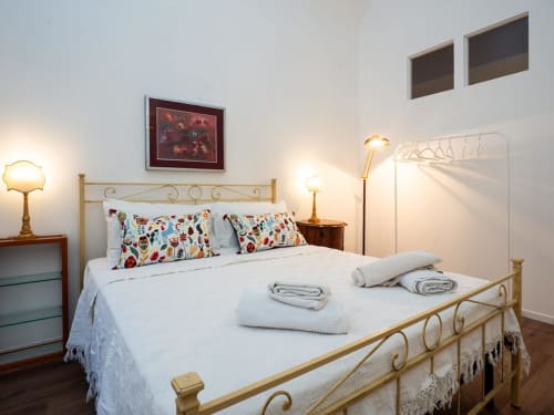 Elegante camera da letto presso SleepWithMe Luxury B&B a Pisa con letto in ottone, cuscini colorati e illuminazione calda