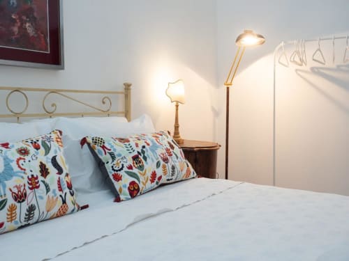 Camera elegante della Luxury B&B SleepWithMe a Pisa con cuscini floreali, testata in ottone e illuminazione calda