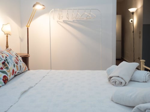 Camera moderna della lussuosa B&B SleepWithMe a Pisa con biancheria bianca, cuscini decorativi, scaffale metallico e illuminazione d'atmosfera