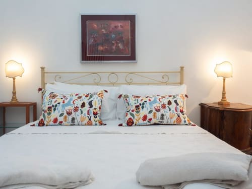 Camera elegante del SleepWithMe Luxury B&B a Pisa con testiera in ottone ornamentale, cuscini floreali e illuminazione ambientale