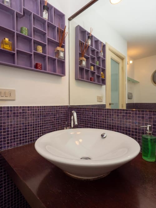 Bagno moderno con scaffalature viola, lavabo rotondo a vessel e rivestimento in scuro presso il lussuoso B&B SleepWithMe a Pisa