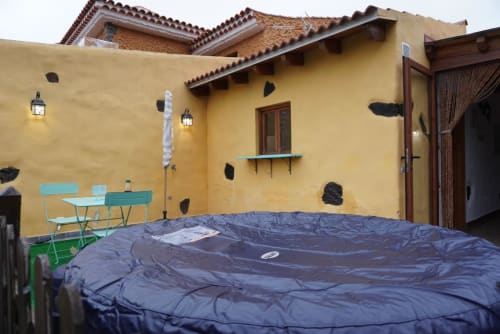 Cottage courtyard at Casonas de Marengo with yellow walls, covered trampoline, turquoise furniture, and mountain views in